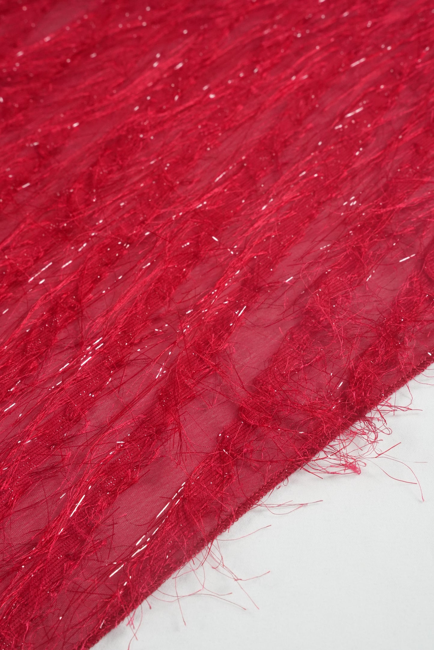 Close up of a bright red saree featuring threadwork that creates the illusion of 3D feathers.