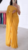 Model taking a selfie wearing a rose gold sequin crop top, draped in a bright yellow saree. The saree has silver threading sewn throughout, giving a shimmery appearance.