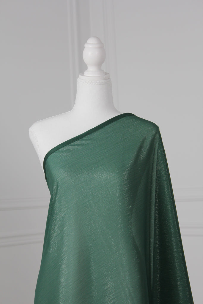 Emerald green saree draped on a mannequin. The saree has silver threading sewn throughout, giving a shimmery appearance.
