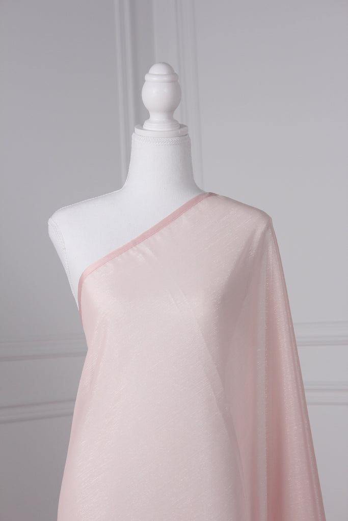 Baby pink saree draped on a mannequin. The saree has silver threading sewn throughout, giving a shimmery appearance.