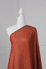 Dark orange saree draped on a mannequin. The saree has silver threading sewn throughout, giving a shimmery appearance.