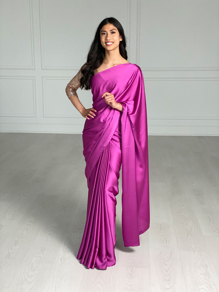 Model wearing a 3/4 sleeve rose gold v-neck sequin crop top and draped in a magenta satin silk saree.