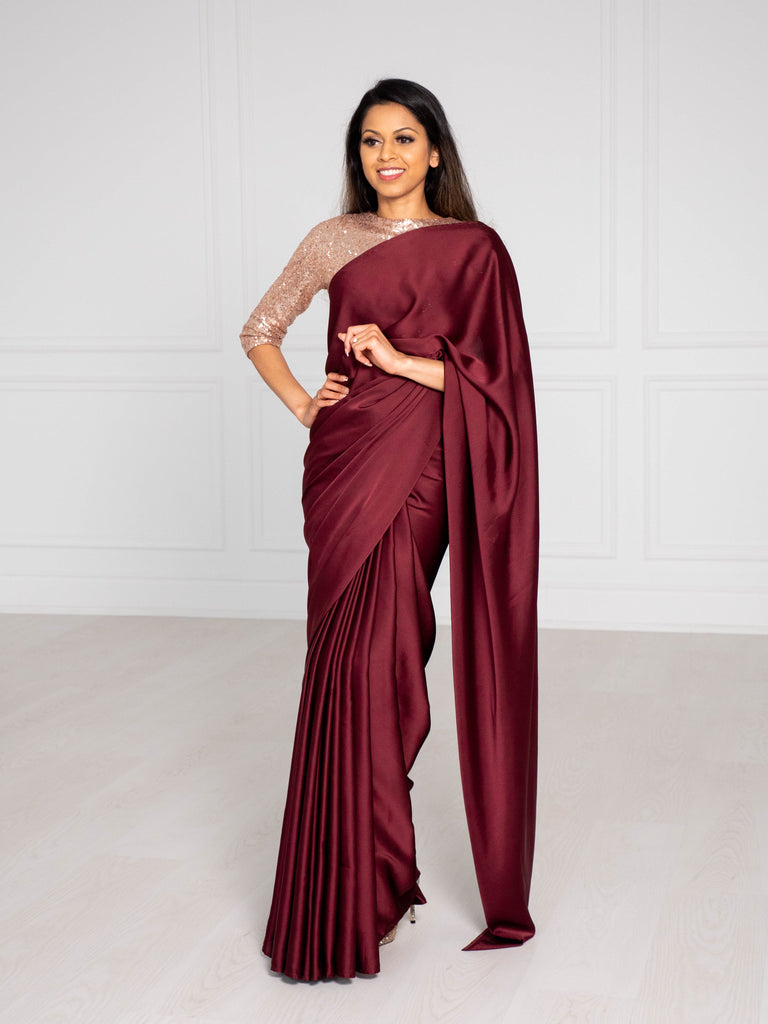 Model wearing a 3/4 sleeve rose gold sequin crop top and draped in a maroon/burgundy satin silk saree.