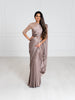 Model wearing a 3/4 sleeve rose gold sequin crop top and draped in a mauve grey satin silk saree. Model is also wearing a gold waist chain with pearls.