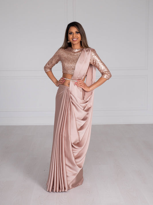 Model wearing a 3/4 sleeve rose gold sequin crop top and draped in a rose gold satin silk saree. Model is also wearing a silver waist chain.