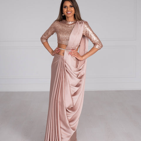 Model wearing a 3/4 sleeve rose gold sequin crop top and draped in a rose gold satin silk saree. Model is also wearing a silver waist chain.