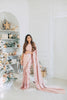 Model wearing a 3/4 sleeve rose gold sequin crop top and draped in a blush pink satin silk saree. Christmas themed background.